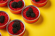 Tin cans of red caviar with berry decorations on a yellow background, a fish delicacy of sturgeon