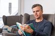 © Peter - handsome 40s single man sits in an comfy  grey armchair and reads