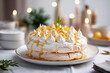 Orange Pavlova Cake topped with citrus sauce, zest and mini meringues crown on a tray. Horizontal, side view. Festive atmosphere.