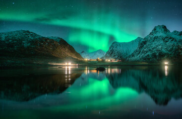 Wall Mural - aurora borealis, snowy mountains, sea, fjord, reflection in water, street lights at starry winter ni