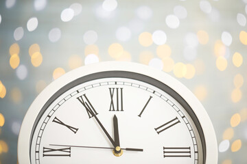 Wall Mural - Clock showing five minutes until midnight on blurred background, closeup. New Year countdown