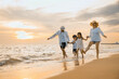 © sorapop - People of father, mother, children son and daughter family of four holding hands together walking outdoor, Happy family having fun running on a sandy beach at sunset, tropical summer travel vacations