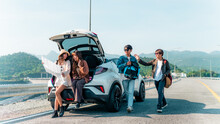 Group Of Asian Generation Z People Friends Sitting On Car Trunk Looking Beautiful Nature Of Countryside. Man And Woman Friendship Enjoy And Fun Outdoor Lifestyle Road Trip On Summer Holiday Vacation.
