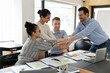 © fizkes - Happy multiethnic colleagues stack join hands engaged in teambuilding activity or training at workplace. Overjoyed multiracial employees have fun feel motivated from shared success or achievement.