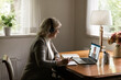 © fizkes - Remote learning for seniors. Focused aged female in modern headset study online on retirement watching webinar training on laptop screen from home taking notes of young woman tutor coach online speech