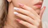 Female hands with long nails with glitter nail polish. Long nails peach color near face. Stylish fashion manicure.