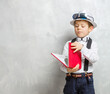 little schoolboy with a book on gray color background