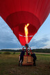 A group of men prepare a hot air balloon for flight using a gas burner and a fan.