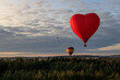 Three hot air balloons with people flies over forests and fields in the morning at dawn