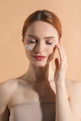 Poster - Beautiful young woman with sun protection cream on her face against beige background