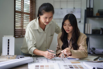 Wall Mural - Two female architects discuss interior design building project and use divider compass on blueprint