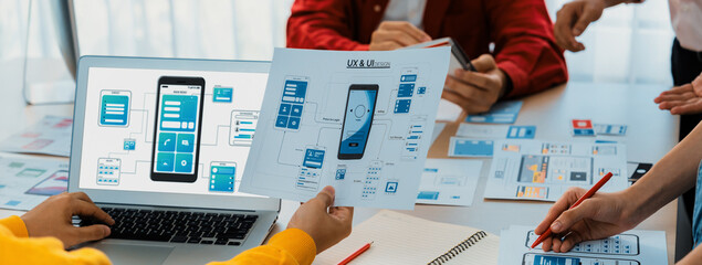 Panorama banner of startup UX developer or company employee design user interface or UI prototype for mobile application or website software with software display on laptop monitor in office. Synergic