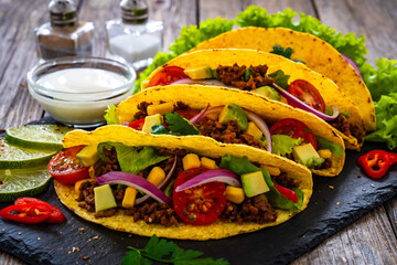 Wall Mural - Tacos with ground beef, avocado, corn and fresh vegetables on wooden table 