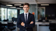 © Yuwarin - Portrait of happy businessman looks at camera on the office blurred background