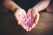 Woman's hands hold the pink ribbon of breast cancer awareness, commitment to health and hope on World Cancer Day.