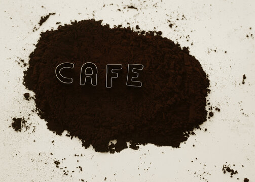 cafe  iron word made from metallic letters. coffee powder backdrop. shredded roasted ground coffee and arabica grain pieces with splash of brown dust. isolated on transparent background. silver metal