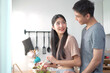 © DG PhotoStock - Happy cheerful Asian young couple preparing a vegetable salad in kitchen together in weekend.