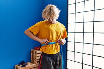 Sticker - Young blond man measuring waist at sport center