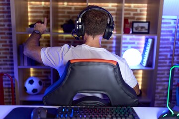 Sticker - Middle age man with beard playing video games wearing headphones posing backwards pointing ahead with finger hand