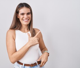 Wall Mural - Hispanic young woman standing over white background cheerful with a smile on face pointing with hand and finger up to the side with happy and natural expression