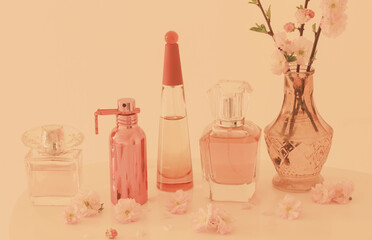 Wall Mural - branches of blossoming almonds in  vase and perfumes on  peach background