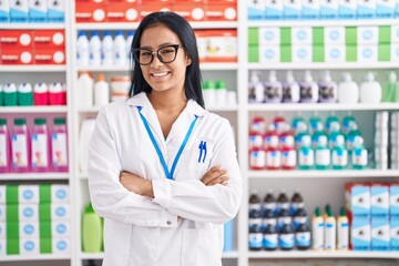 Wall Mural - Hispanic woman working at pharmacy drugstore happy face smiling with crossed arms looking at the camera. positive person.