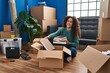 © Krakenimages.com - Young beautiful hispanic woman smiling confident putting books on cardboard box at new home
