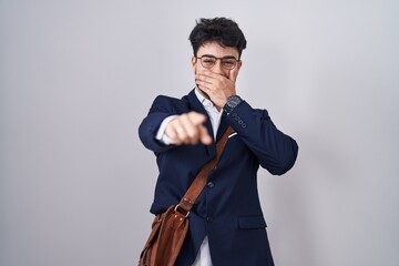 Wall Mural - Hispanic man with beard wearing business clothes laughing at you, pointing finger to the camera with hand over mouth, shame expression