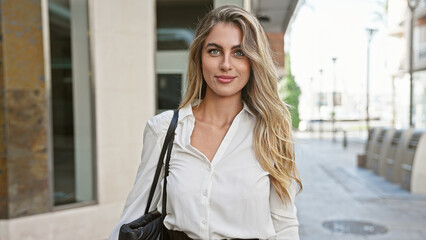 Poster - Radiant young blonde woman, exuding confidence with a sparkling smile, stands outdoors on a sunny city street, enjoying the urban ambiance and spreading positive vibes.