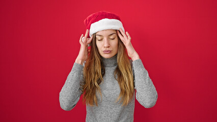 Young caucasian woman wearing christmas hat stressed over isolated red background