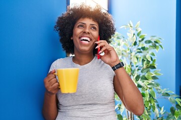 Poster - African american woman talking on smartphone drinking coffee at home