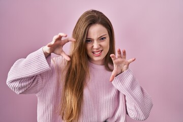 Canvas Print - Young caucasian woman standing over pink background smiling funny doing claw gesture as cat, aggressive and sexy expression