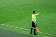 The line referee on the edge of the field with a flag in his hand indicates offside with his hand