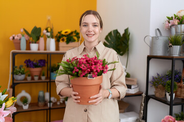 Wall Mural - Young caucasian woman working at florist shop holding plant pot smiling with a happy and cool smile on face. showing teeth.