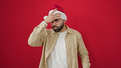 Sticker - Young hispanic man wearing christmas hat having headache over isolated red background