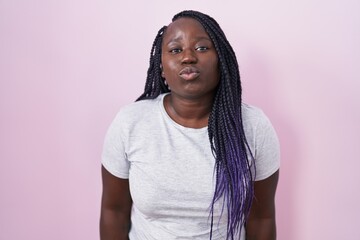 Poster - Young african woman standing over pink background looking at the camera blowing a kiss on air being lovely and sexy. love expression.