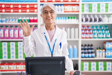 Wall Mural - Middle age woman with tattoos working at pharmacy drugstore showing and pointing up with fingers number five while smiling confident and happy.