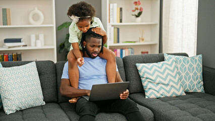 Wall Mural - African american father and daughter using computer with child on shoulders at home