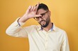 Hispanic young man wearing business clothes and glasses making fun of people with fingers on forehead doing loser gesture mocking and insulting.