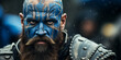 Intense warrior with tribal blue face paint and beard, holding a shield, ready for battle, exemplifies ancient tribal war traditions and strength