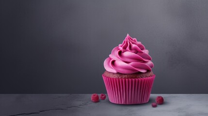 Sticker -  a pink cupcake with pink icing and raspberries on the side of the cupcake is sitting on a gray surface with a gray wall in the background.