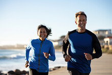 A Happy And Fit Couple Jogging Together By The Beach, Enjoying A Healthy And Active Lifestyle In The Summer Morning.