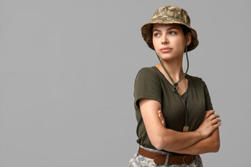 Wall Mural - Confident young female soldier in uniform on grey background