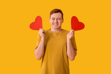 Sticker - Happy young man with red paper hearts on yellow background