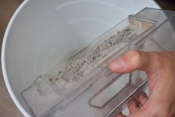 Wall Mural - Cleaning the filter of the vacuum robot cleaner from dirt, close-up.