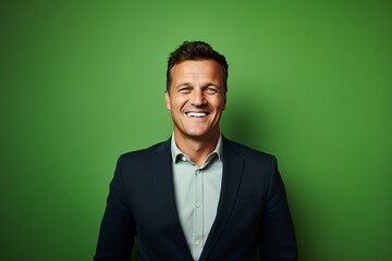 portrait of a smiling mature businessman standing against a green background.