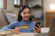 © amnaj - Young asian woman using smartphone and credit card for online shopping at home.