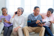 © ultramansk - Happiness of the group females and male elderly talking with Video Call from smart tablet. Senior people are talking and enjoy together at the living room. Joyful retired friends enjoying relaxation.