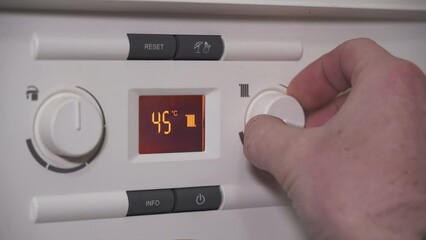 Lowering water temperature radiator or heating on boiler, closeup of screen and hand