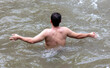 A man bathes in a mountain river. Back view